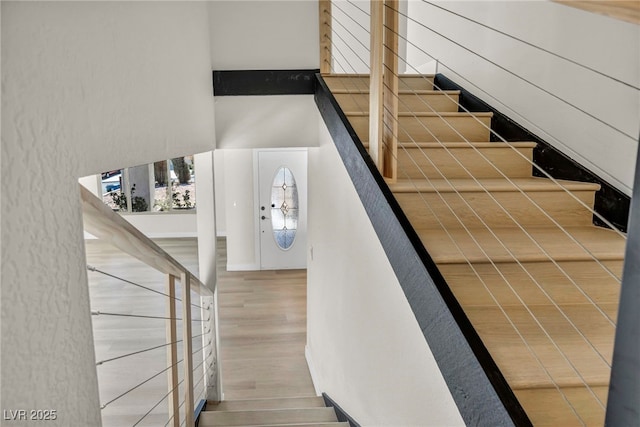 stairs with a high ceiling and wood finished floors