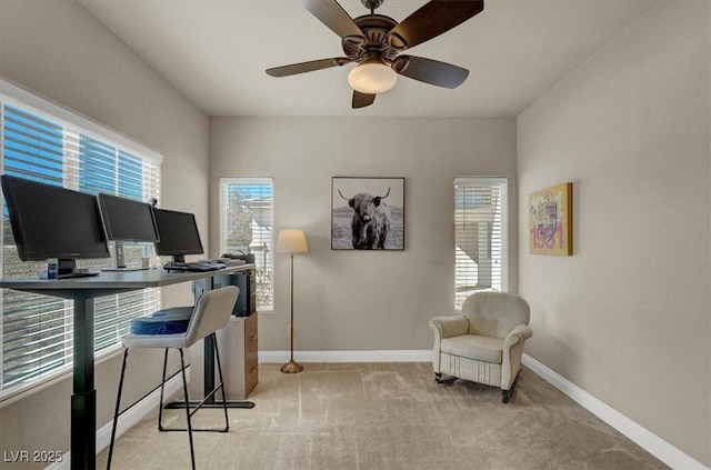 office space featuring light colored carpet, baseboards, and ceiling fan