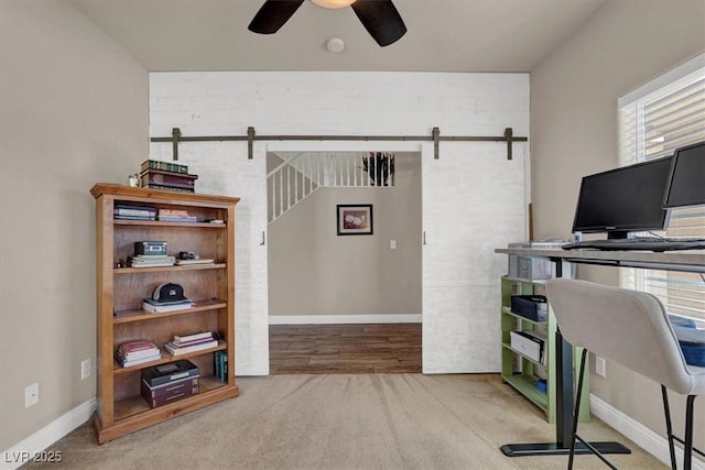 carpeted office with a barn door, a healthy amount of sunlight, and ceiling fan