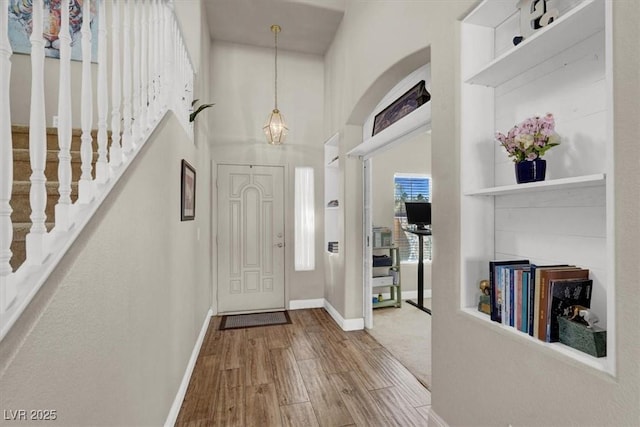 entryway with baseboards, a high ceiling, and wood finished floors