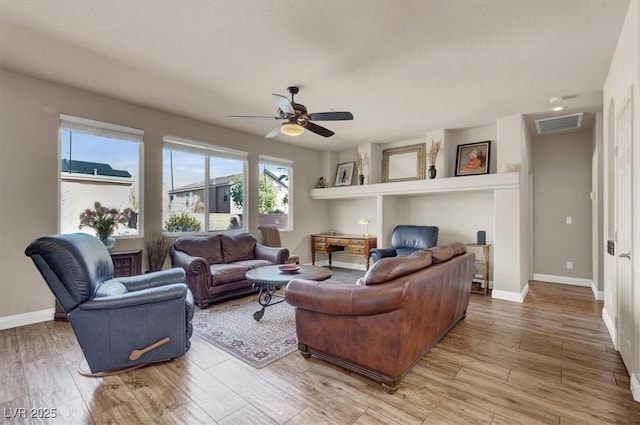 living area featuring visible vents, a ceiling fan, light wood-type flooring, and baseboards