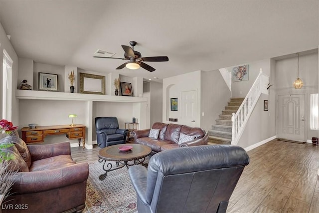 living room featuring visible vents, stairway, a ceiling fan, and wood finished floors