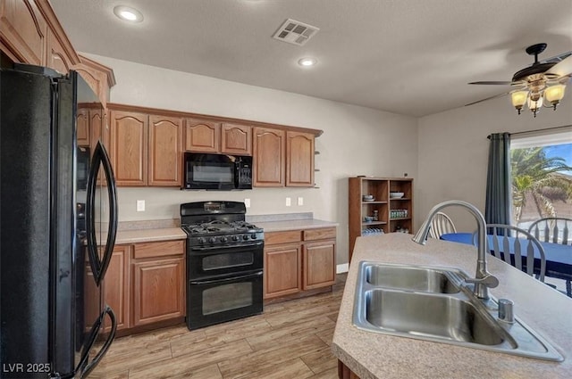 kitchen with visible vents, black appliances, a sink, light wood-style floors, and light countertops