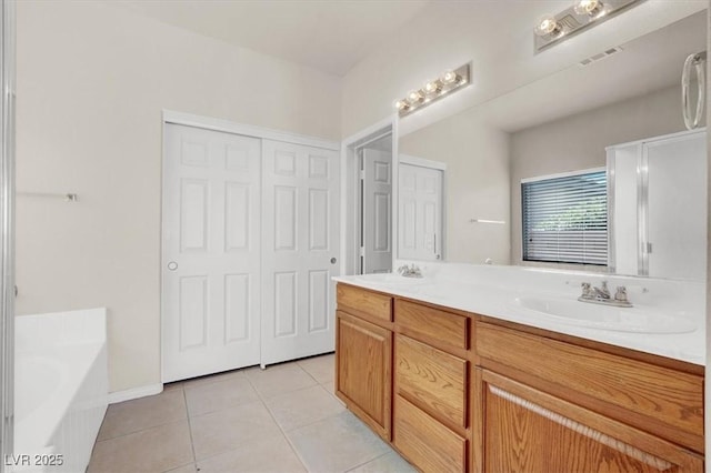 bathroom featuring tile patterned flooring, visible vents, double vanity, a bath, and a sink