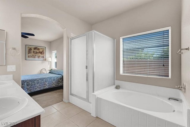 bathroom featuring double vanity, a bath, a shower stall, and tile patterned flooring