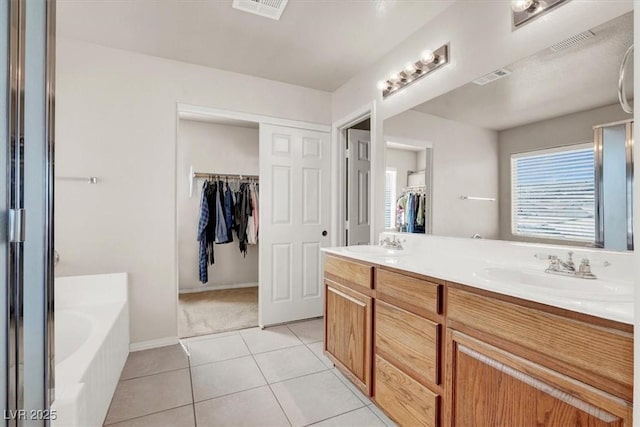 bathroom with tile patterned flooring, visible vents, a garden tub, and a sink