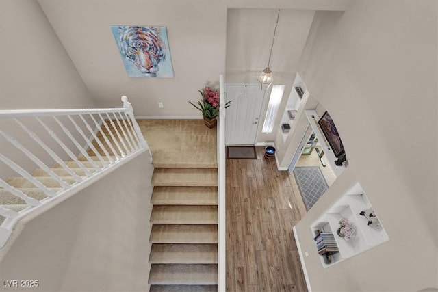 entryway with stairway, a towering ceiling, baseboards, and wood finished floors