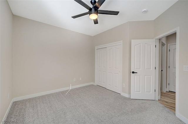 unfurnished bedroom with a closet, baseboards, light colored carpet, and a ceiling fan