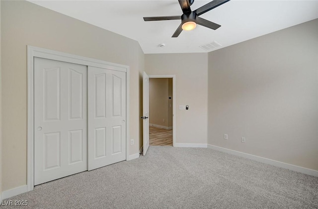 unfurnished bedroom with visible vents, baseboards, light colored carpet, and a closet