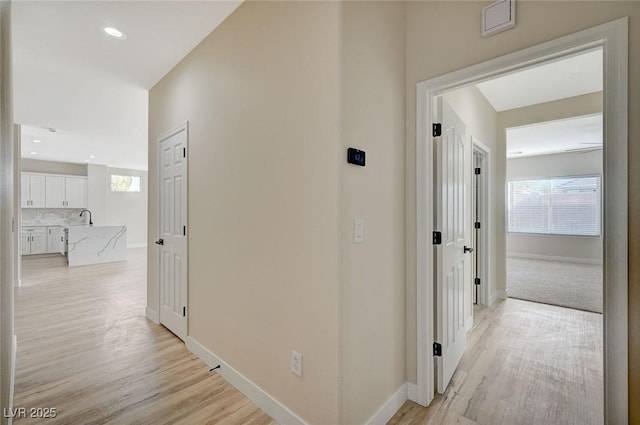 hall featuring recessed lighting, baseboards, light wood-style floors, and a healthy amount of sunlight