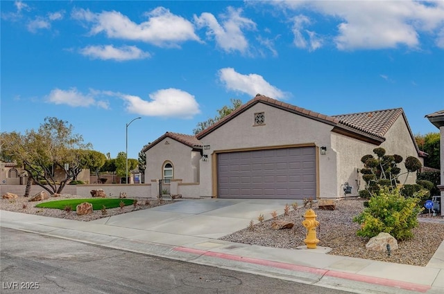 mediterranean / spanish-style home with concrete driveway, a tiled roof, an attached garage, and stucco siding