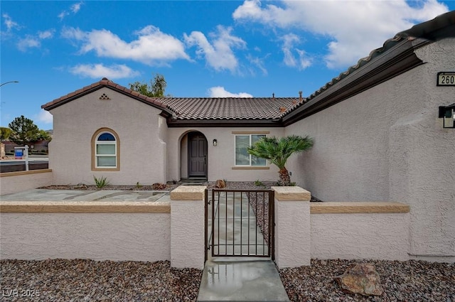 view of front of home featuring a tile roof, a gate, a fenced front yard, and stucco siding