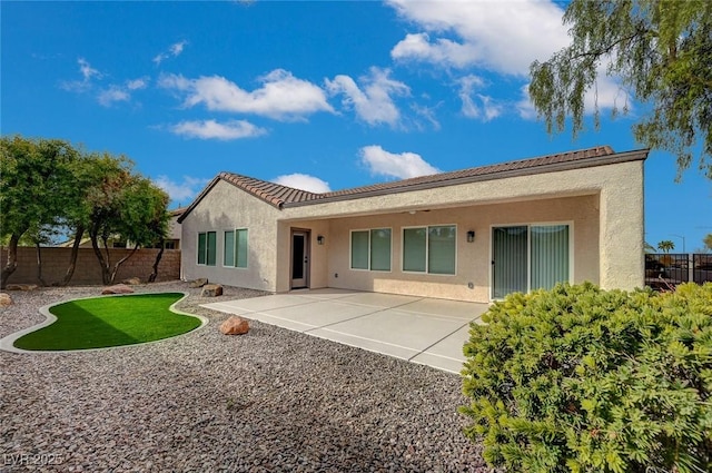 rear view of property featuring a patio area, a tiled roof, a fenced backyard, and stucco siding