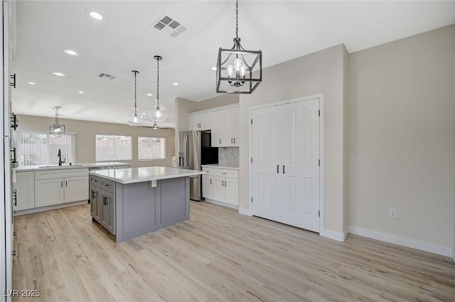 kitchen featuring visible vents, a kitchen island, stainless steel fridge with ice dispenser, light countertops, and light wood-style flooring