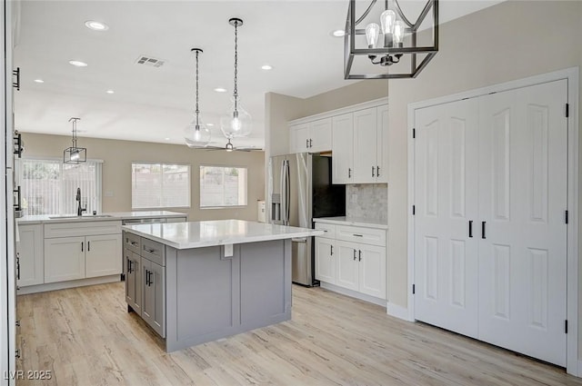 kitchen with a sink, a kitchen island, a wealth of natural light, and stainless steel refrigerator with ice dispenser