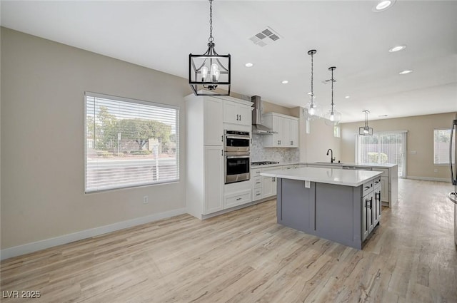 kitchen with a sink, backsplash, gas stovetop, stainless steel double oven, and light countertops