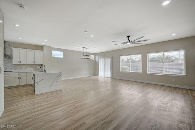 unfurnished living room with a ceiling fan, recessed lighting, baseboards, and light wood finished floors