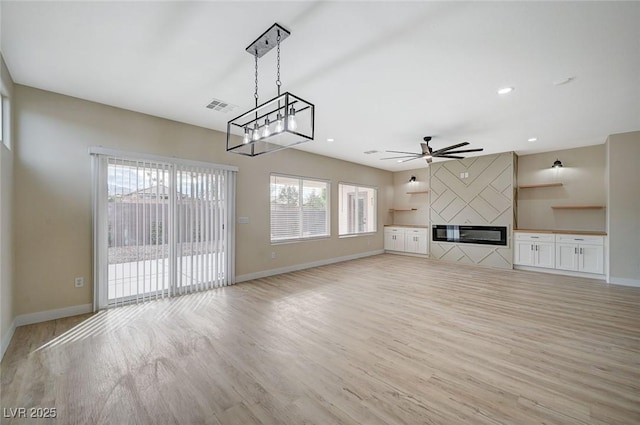 unfurnished living room with a fireplace, light wood-type flooring, and a healthy amount of sunlight