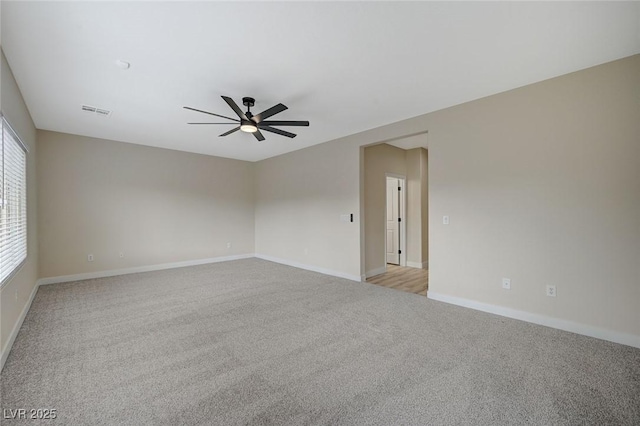 spare room with baseboards, light colored carpet, visible vents, and ceiling fan