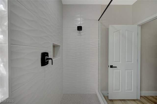 full bath with a tile shower and wood finished floors