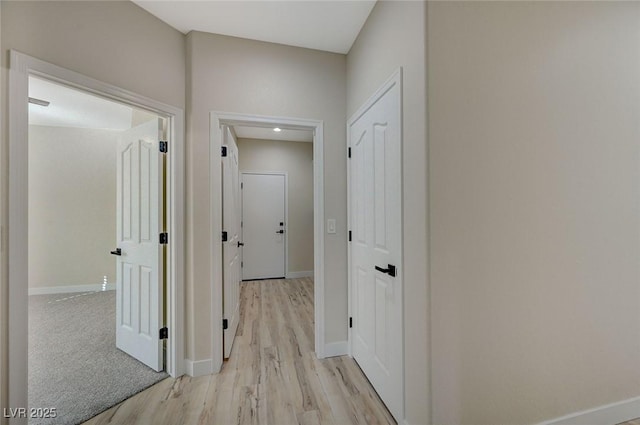 hallway featuring baseboards and light wood finished floors