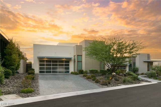 contemporary home featuring stucco siding, decorative driveway, and a garage