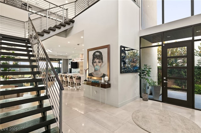 entrance foyer featuring tile patterned flooring, a high ceiling, stairs, and baseboards