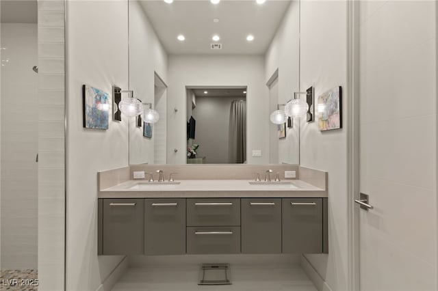 bathroom with double vanity, recessed lighting, tiled shower, and a sink