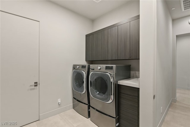 clothes washing area with visible vents, washer and clothes dryer, cabinet space, light tile patterned floors, and baseboards