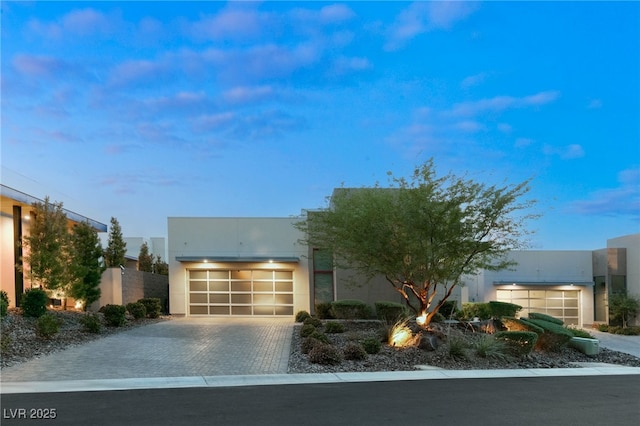 contemporary house featuring decorative driveway, an attached garage, and stucco siding