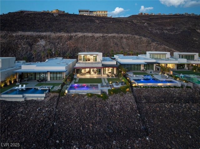 rear view of property with a patio area, an outdoor pool, and a jacuzzi