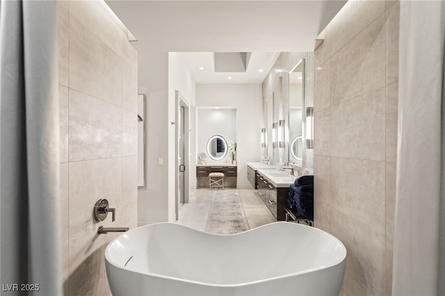 full bath with a soaking tub, tile walls, and vanity