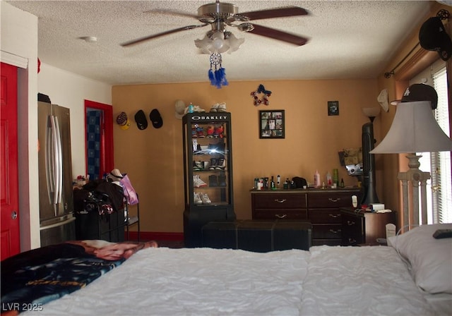 bedroom with a ceiling fan, freestanding refrigerator, and a textured ceiling