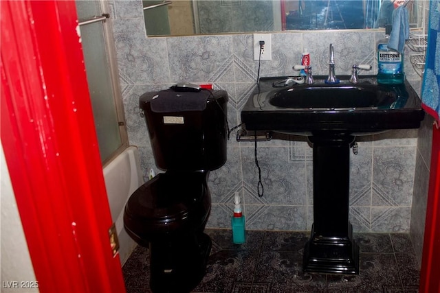 bathroom featuring backsplash, toilet, bathing tub / shower combination, and a sink