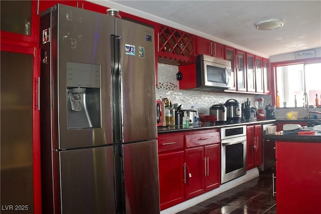 kitchen featuring a sink, dark brown cabinets, appliances with stainless steel finishes, dark countertops, and backsplash