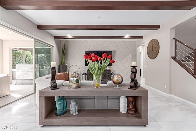 interior space featuring beam ceiling, baseboards, marble finish floor, and an accent wall