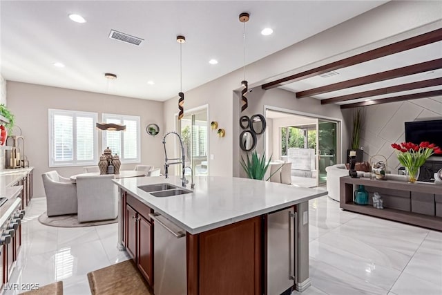 kitchen featuring visible vents, a sink, light countertops, stainless steel dishwasher, and open floor plan