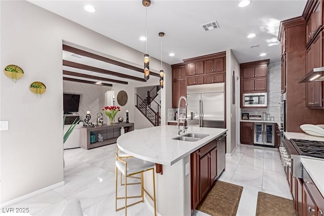 kitchen with beverage cooler, visible vents, built in appliances, decorative light fixtures, and tasteful backsplash