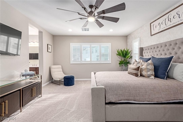 bedroom with baseboards, visible vents, ensuite bath, ceiling fan, and light carpet