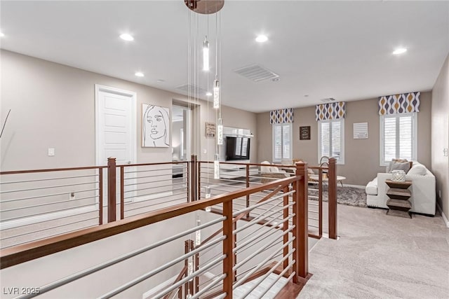 hallway with visible vents, baseboards, light colored carpet, an upstairs landing, and recessed lighting