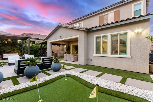 rear view of house featuring a tiled roof, stucco siding, a patio, and an outdoor hangout area