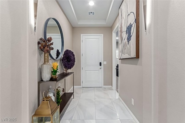 entryway with light tile patterned floors, visible vents, a tray ceiling, and baseboards