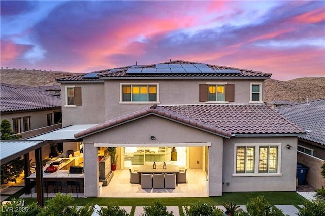 rear view of house featuring outdoor lounge area, a patio, a tile roof, and stucco siding