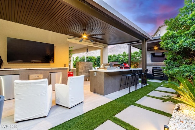 view of patio / terrace with outdoor wet bar, exterior kitchen, and a ceiling fan