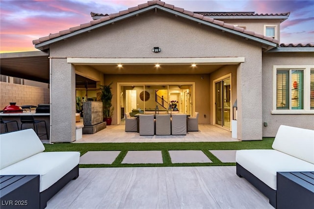 back of property featuring area for grilling, stucco siding, an outdoor hangout area, and a patio