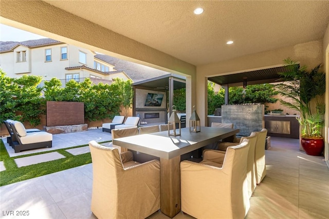 view of patio with outdoor dining space and an outdoor living space with a fireplace