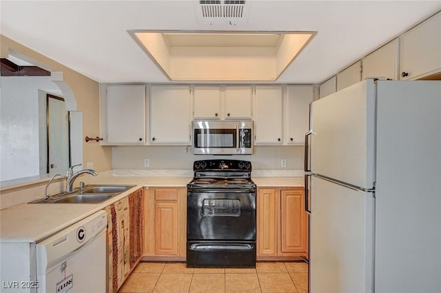 kitchen featuring white appliances, light tile patterned floors, visible vents, a sink, and a raised ceiling