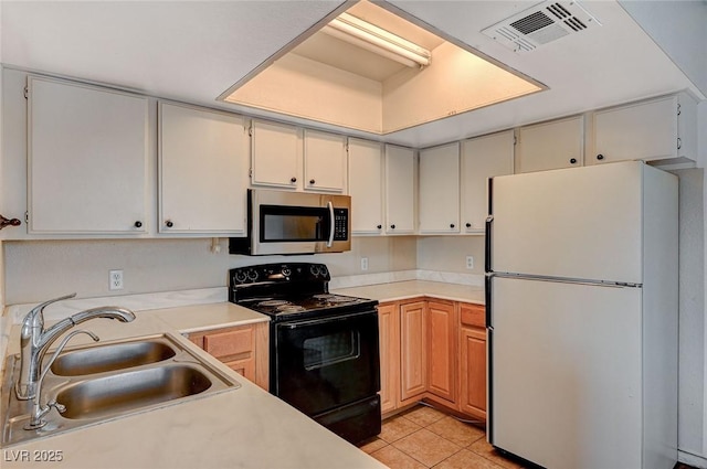 kitchen featuring visible vents, black electric range oven, a sink, stainless steel microwave, and freestanding refrigerator