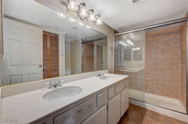 bathroom with tile patterned flooring, a stall shower, and a sink