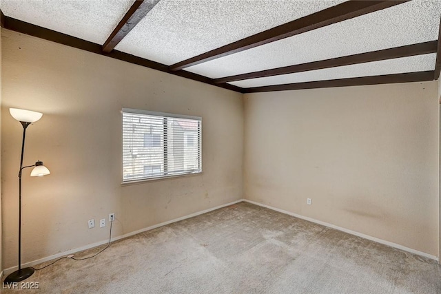 carpeted spare room featuring beam ceiling, baseboards, and a textured ceiling